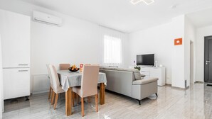 En moderne, minimalistisk stue med spiseplads, sofa og fjernsyn.