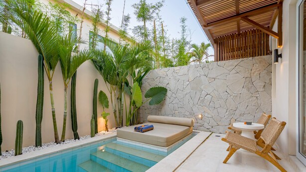 A private pool area with a stone wall, a small seating area with a mattress and cushions, and two wicker chairs. - Villa Palima (Canggu)