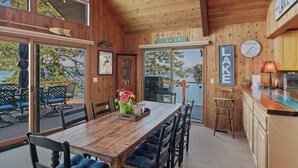 Una cabaña de madera con comedor, cocina y vistas a un lago.
