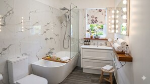Een moderne badkamer met een vrijstaand bad, een toilet, een wastafel met spiegel en een raam met uitzicht op groen.