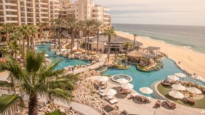 Et resort med flere swimmingpools, palmer og en strand.
