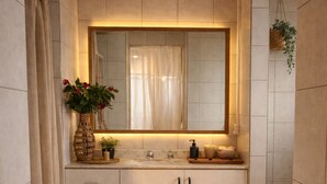 Ein Badezimmer mit einem großen Spiegel, einem Waschbecken und einem Holzkästen.