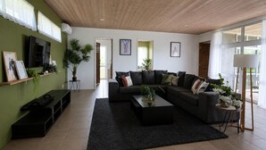 Ein modernes Wohnzimmer mit einem Ecksofa, einem Flachbildfernseher, einem Couchtisch und einem großen Fenster.