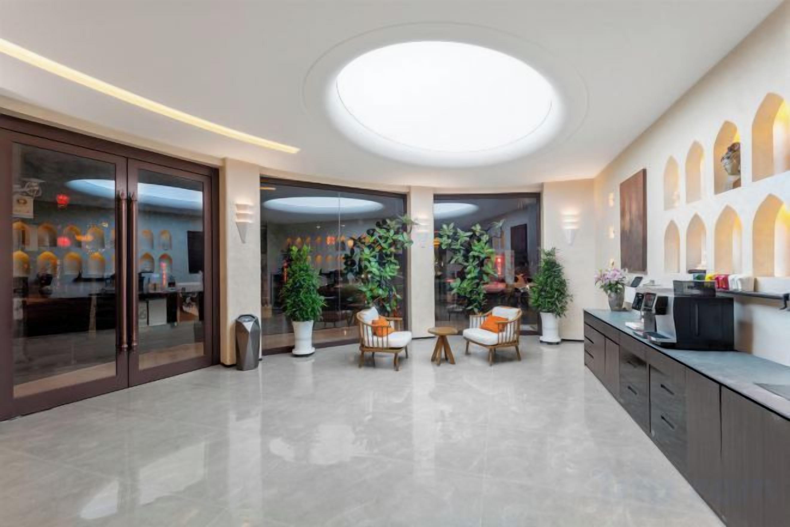 A hotel lobby with a central seating area, a reception desk, and a large circular skylight.