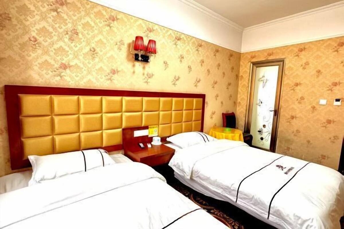 Una habitación de hotel con dos camas, cabecera de madera, mesita de noche y espejo.