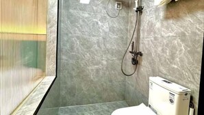 Een moderne badkamer met een douchecabine van glas, een toilet en een handdoekhouder.