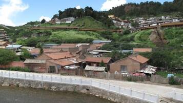 A riverside village with traditional houses, a white bridge, and a stone wall.