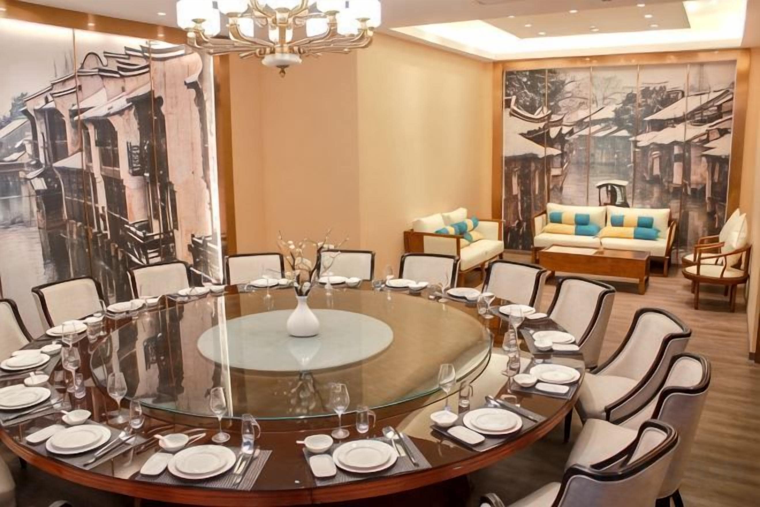 A round dining table with chairs, a chandelier, and a painting on the wall.