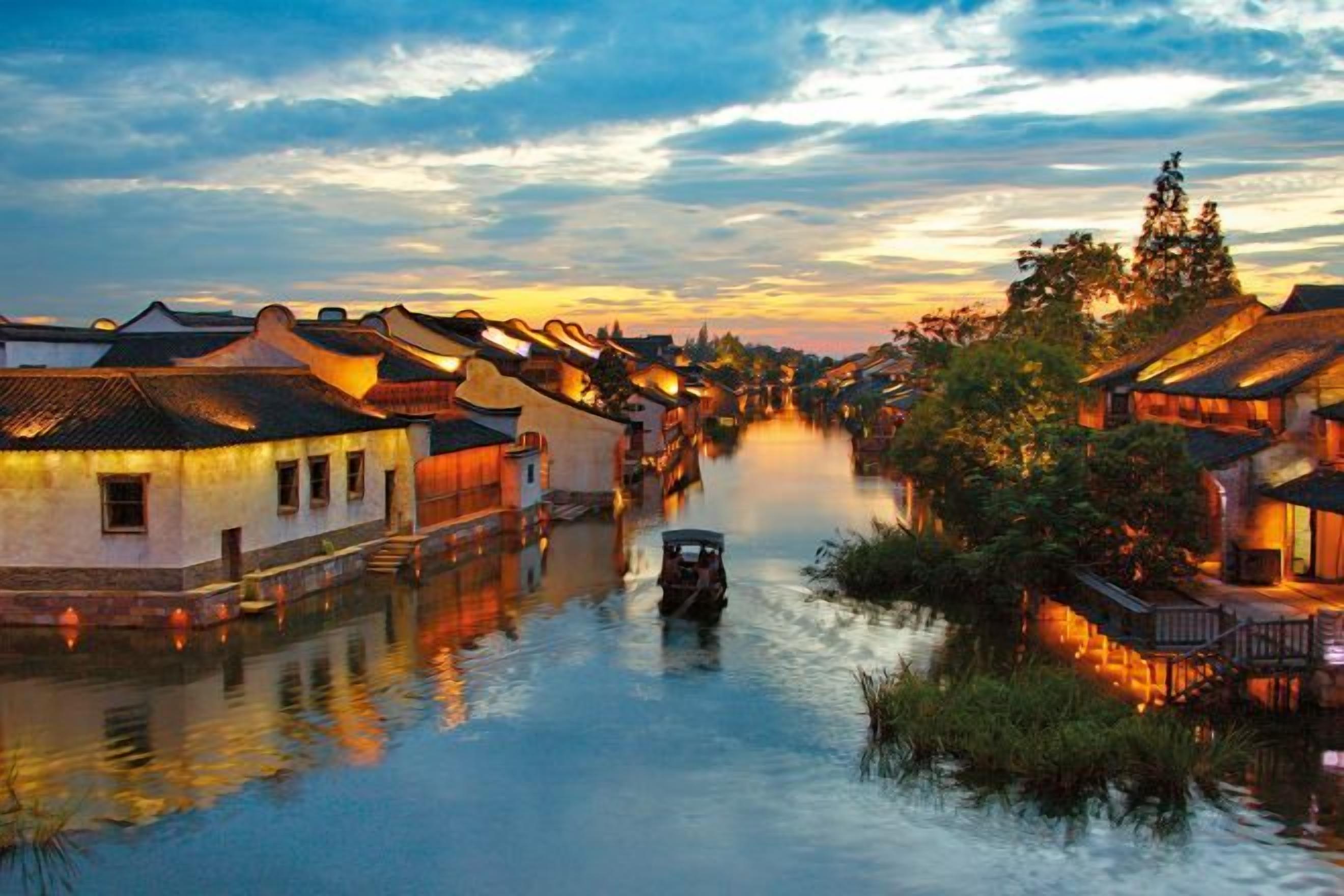 Un pueblo tradicional a orillas del río, con edificios a lo largo del agua, un bote y un cielo despejado.