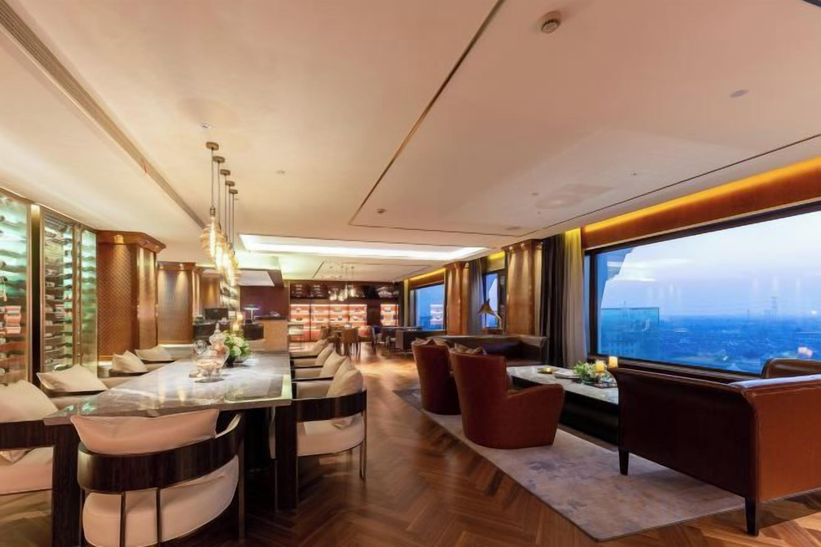 A modern interior with a dining area, seating, and a large window offering a view.