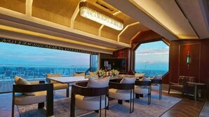 Un interior moderno con comedor, ventanas amplias y vista a la ciudad.