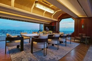 Un interior moderno con comedor, ventanas amplias y vista a la ciudad.