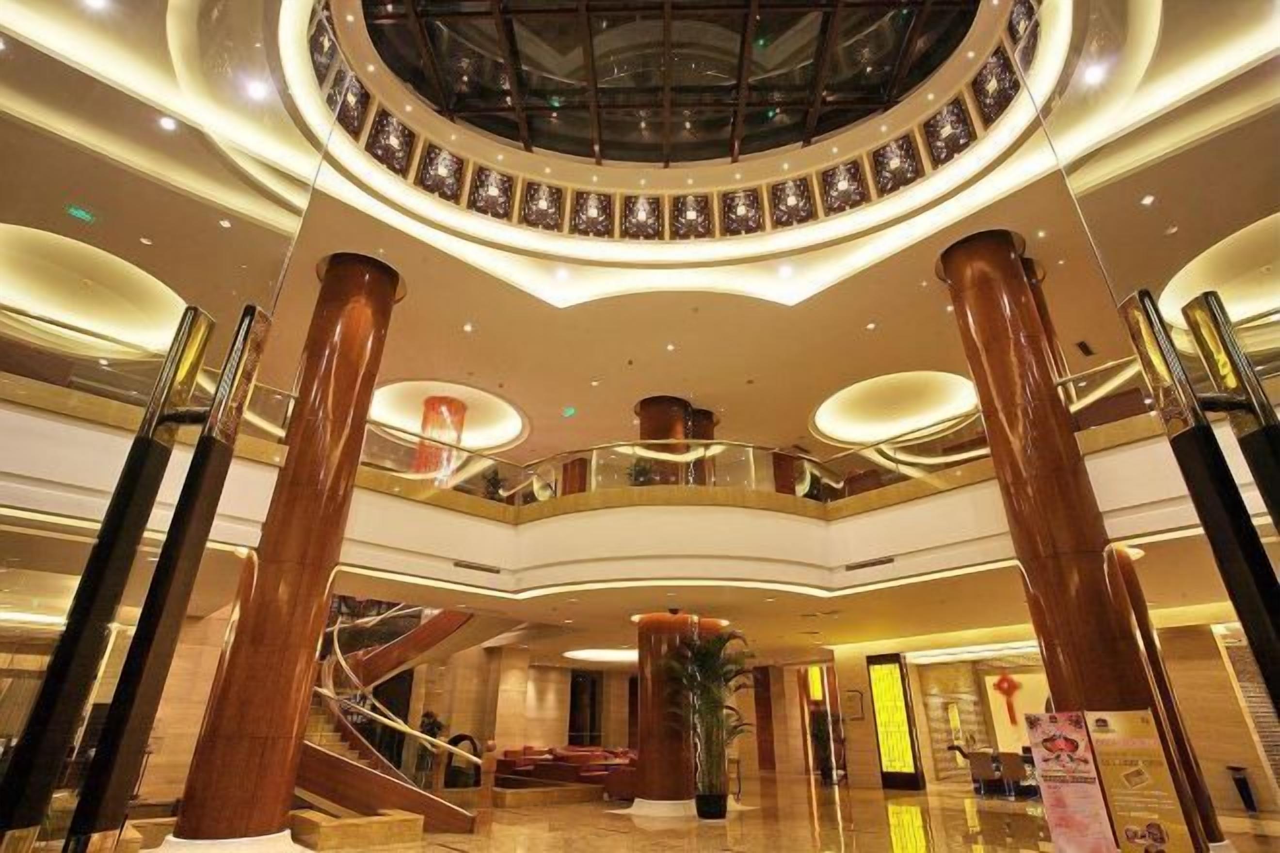 Un vestíbulo amplio con una escalera central, columnas grandes y un tragaluz circular.