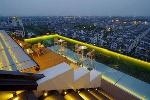 Una terraza en la azotea con asientos exteriores y vistas a la ciudad.