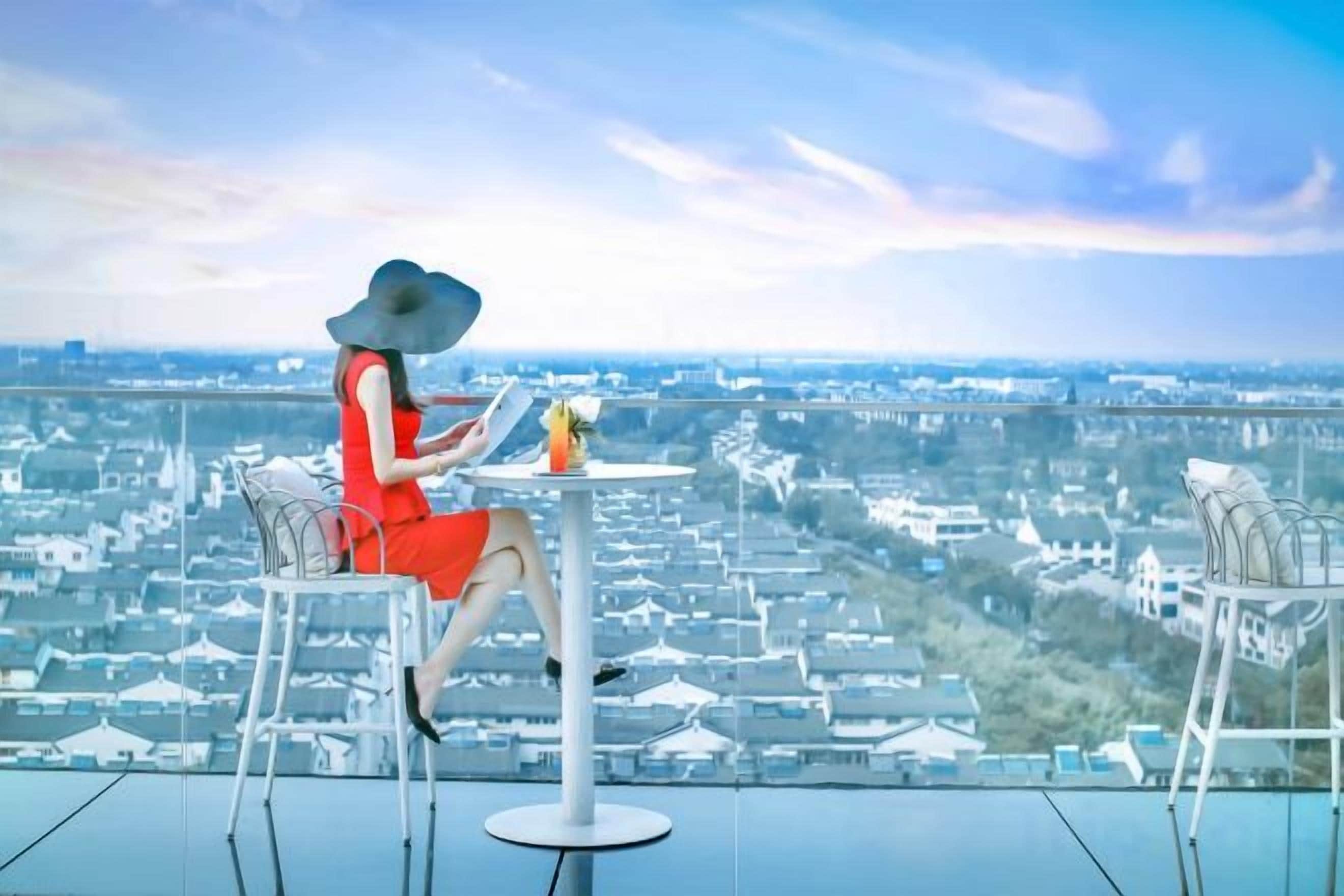 Une personne assise à une table, avec vue sur le paysage urbain.