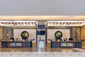 A lobby with two reception desks, a central staircase, and a large wall-mounted globe. - GOLD RIVER-SIDE HOTEL WUZHEN (Tongxiang)