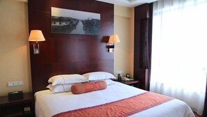A hotel room with a large bed, two bedside lamps, a nightstand, a painting on the wall, and a window with curtains. - GOLD RIVER-SIDE HOTEL WUZHEN (Tongxiang)