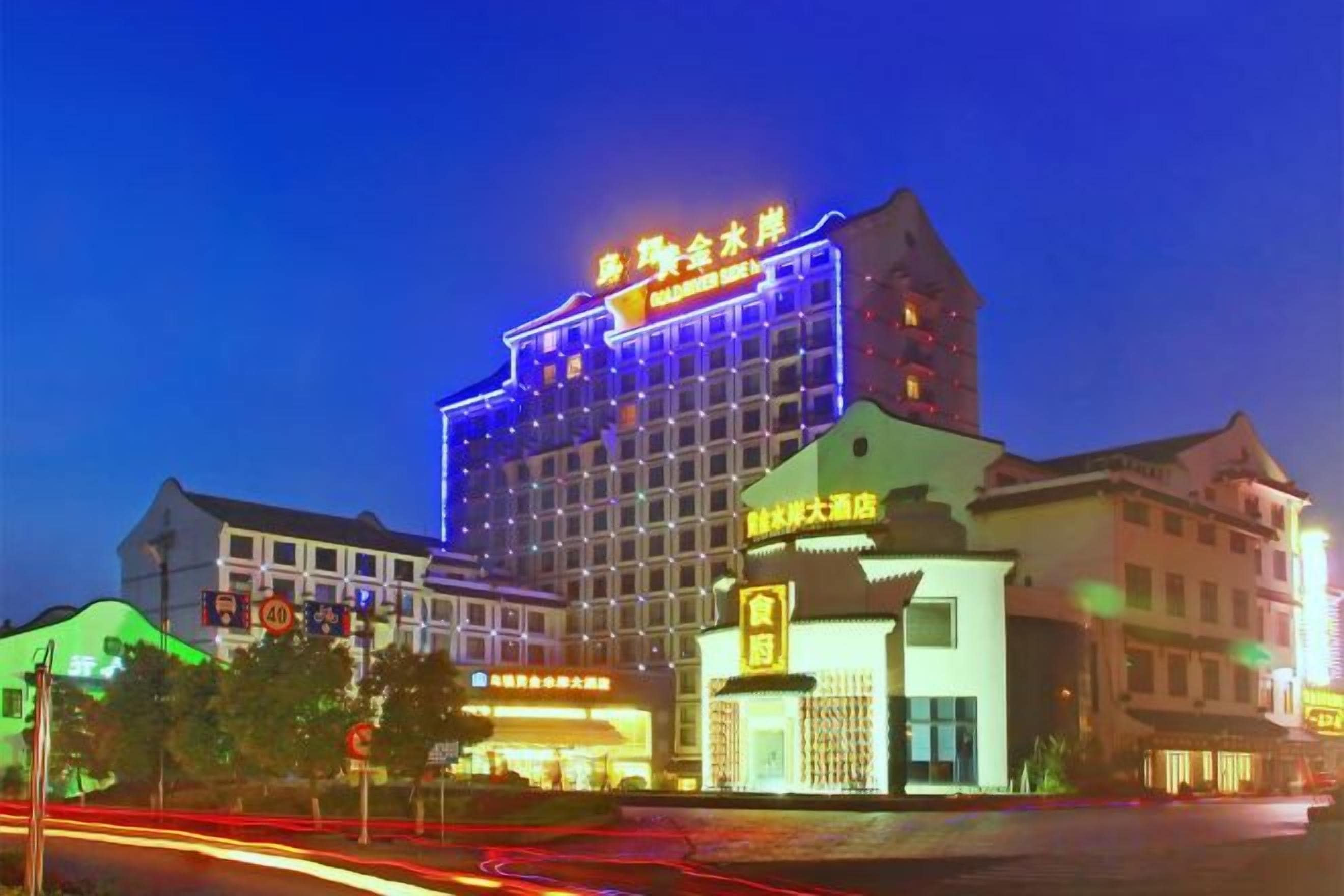 A multi-story hotel with illuminated signage, a prominent entrance, and a street view with traffic lights.