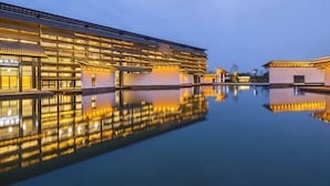 Un edificio moderno con una piscina reflectante al frente.