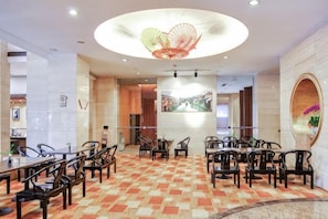 A hotel dining area with round tables and chairs, a patterned carpet, and a large circular light fixture. - GOLD RIVER-SIDE HOTEL WUZHEN (Tongxiang)