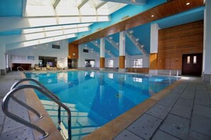 Una piscina interior con tragaluces, paredes de madera y suelo de baldosas.