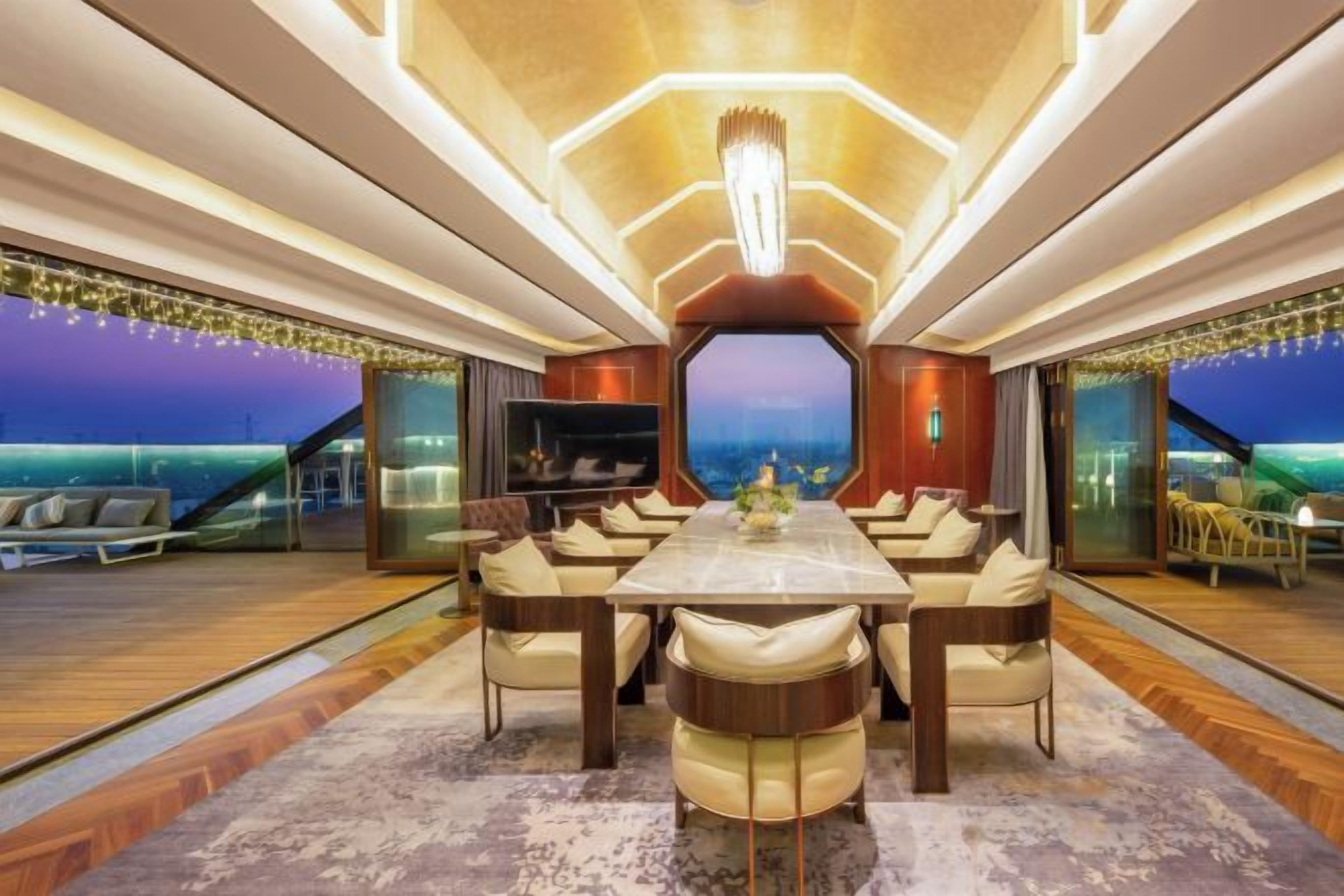 A spacious dining area with a long table and multiple chairs, a large window offering a view, and a modern interior design.