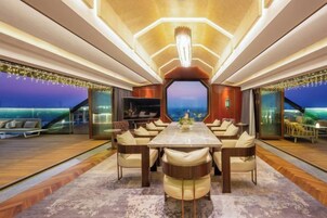 Un comedor amplio con una larga mesa y múltiples sillas, un gran ventanal que ofrece vistas, y un diseño de interiores moderno.