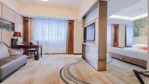 A hotel room with a sofa, a TV mounted on the wall, a bed, and a desk with a lamp. - GOLD RIVER-SIDE HOTEL WUZHEN (Tongxiang)