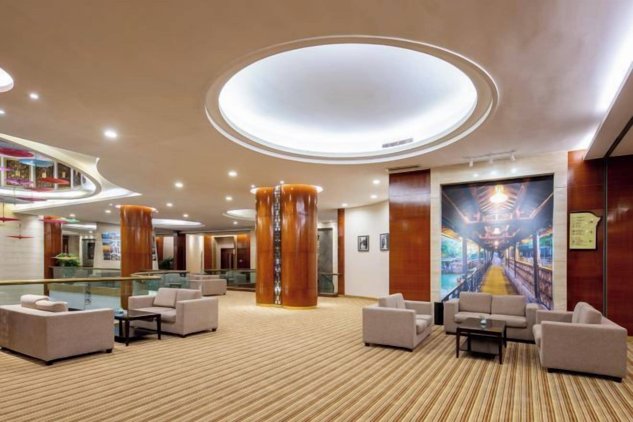 A spacious lobby with a high ceiling, multiple seating areas, and a central column.