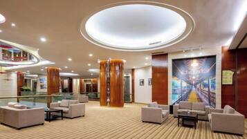 A spacious lobby with a high ceiling, multiple seating areas, and a central column.