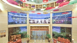 Un vestíbulo de hotel con una escalera central, ventanas amplias y varias zonas de estar.
