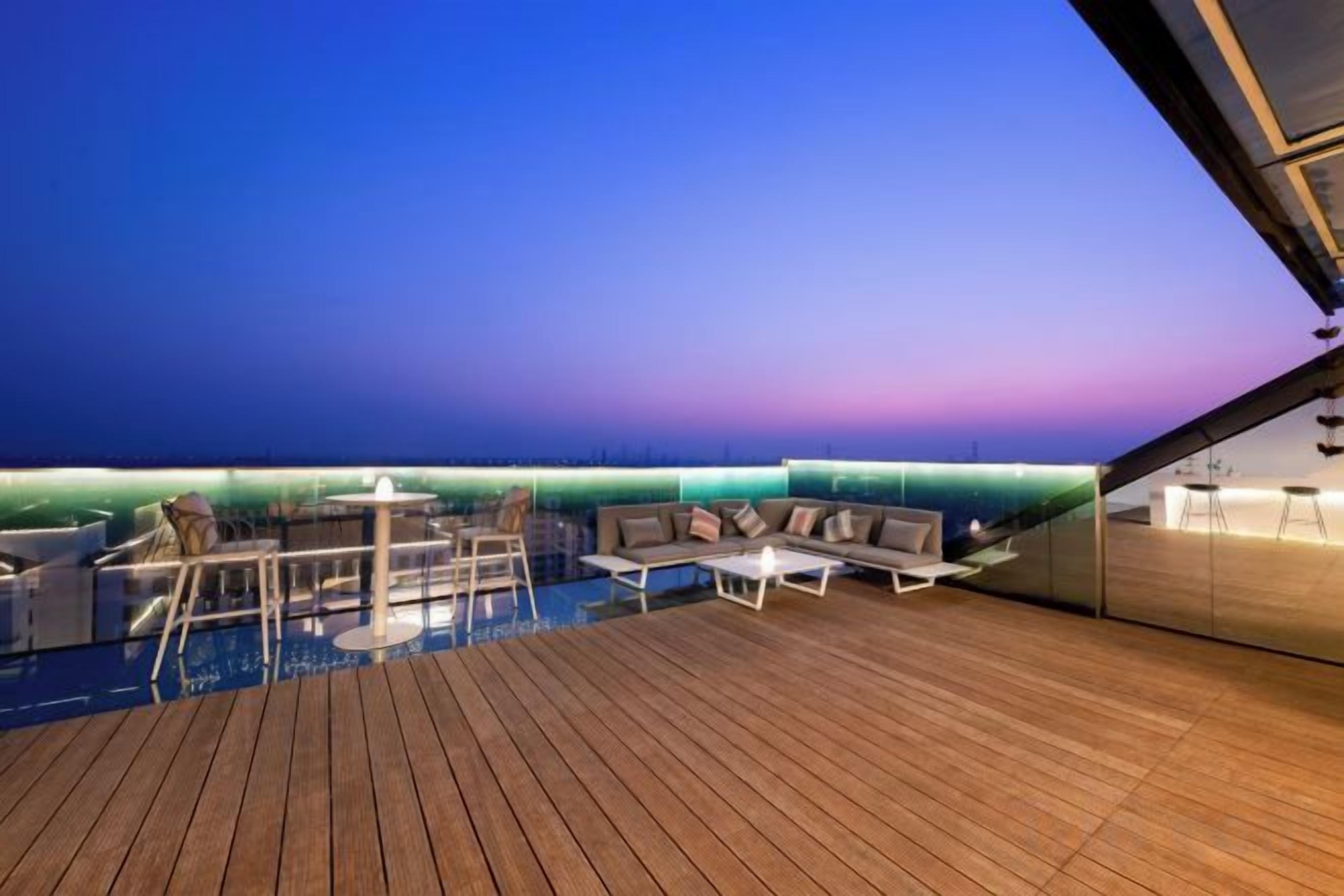 A wooden deck with a pool, seating area, and a bar.