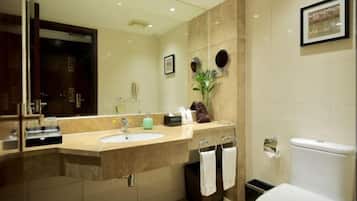 A modern bathroom with a large mirror, a sink, a toilet, and a trash bin.