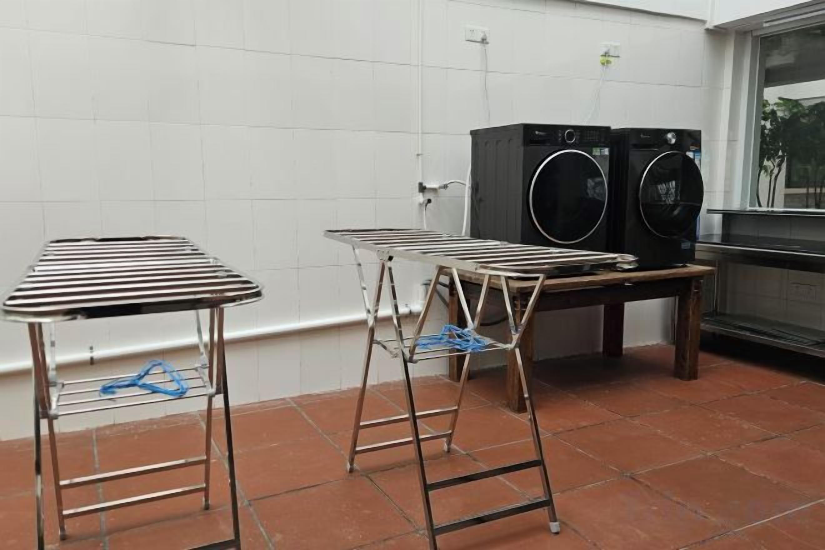 A laundry area with two metal drying racks and two stacked washing machines.