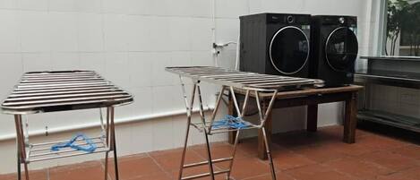 A laundry area with two metal drying racks and two stacked washing machines.