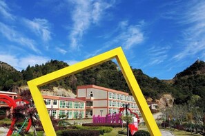 Un edificio de techo plano, rodeado de vegetación y colinas.