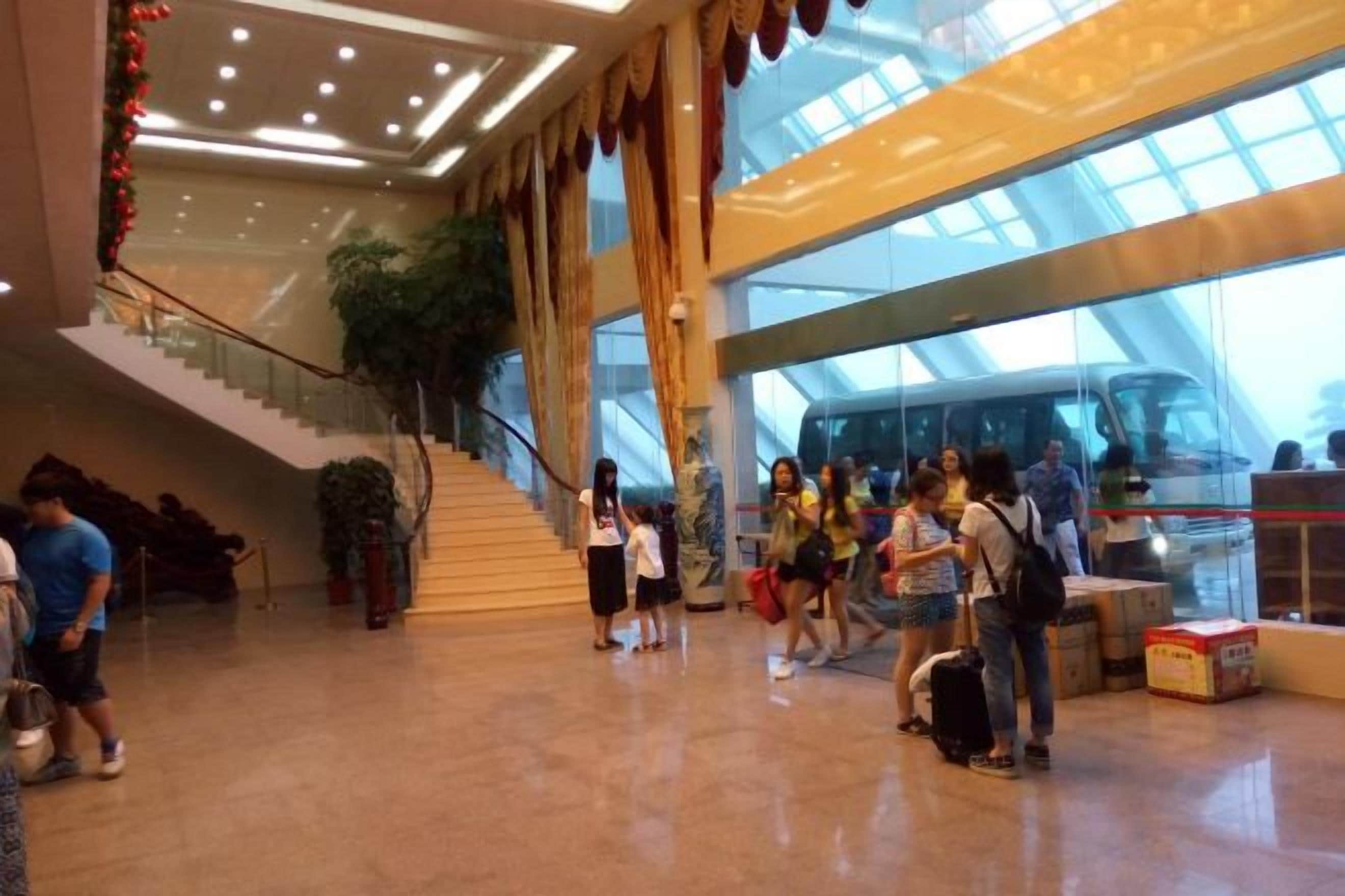 A spacious indoor area with a staircase, a large plant, and a glass wall.