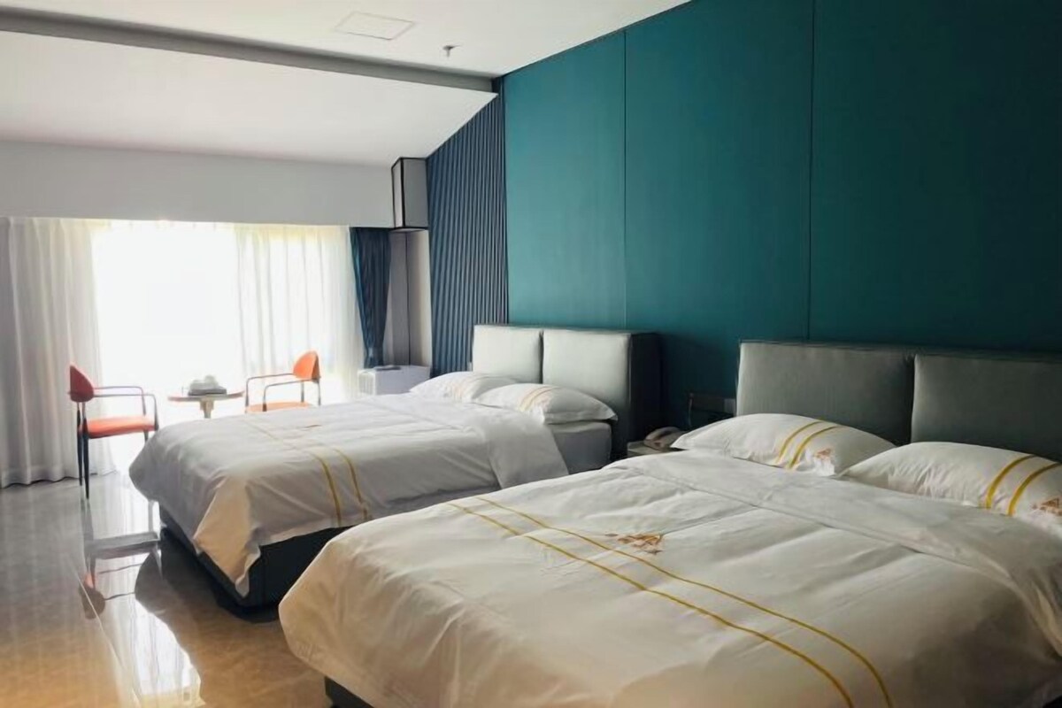 Habitación de hotel con dos camas, un escritorio y una silla.