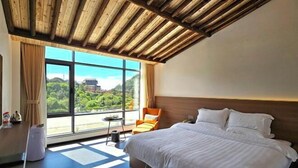 A modern hotel room with a large bed, a view of greenery, and a wooden ceiling. - Naixing Shihu Leisure Mountain Resort (Chaozhou)