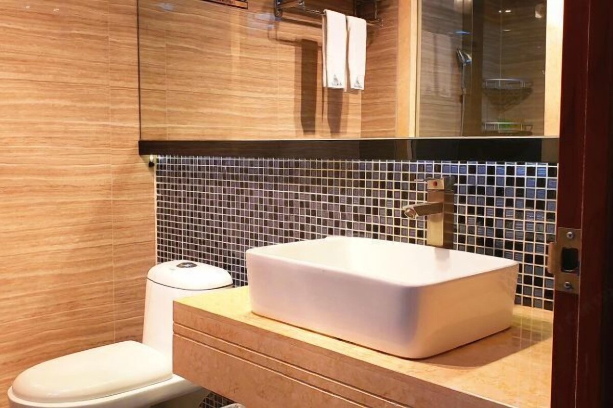 Un baño moderno con un lavabo blanco, tocador de madera y salpicadero de azulejos.