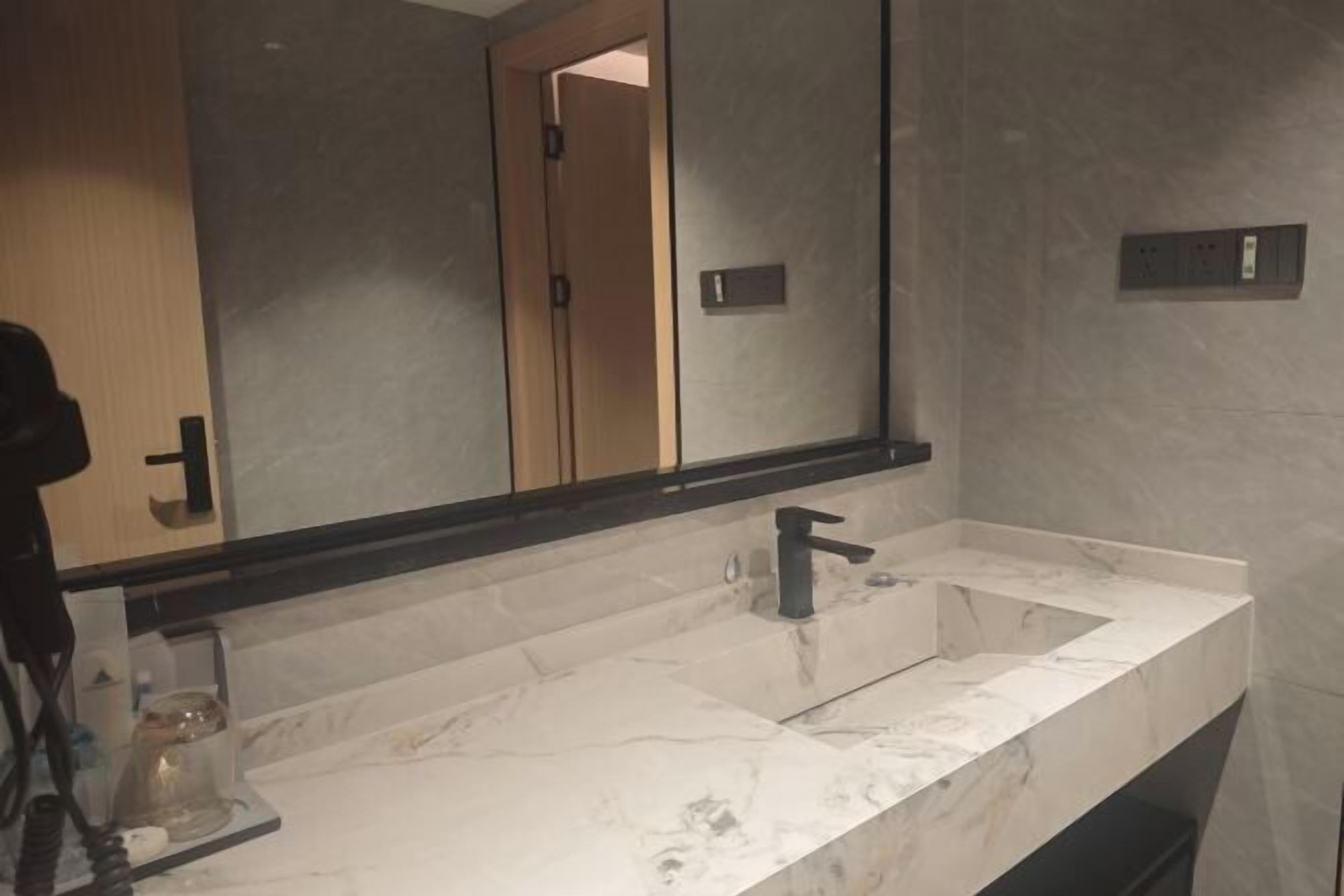 Une salle de bain avec un grand miroir, deux lavabos et un porte-serviettes.