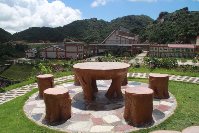 A circular outdoor seating area with a central table and four stools, surrounded by a patterned walkway.