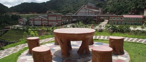 A circular outdoor seating area with a central table and four stools, surrounded by a patterned walkway.