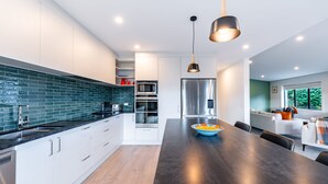 A modern kitchen with white cabinets, a black countertop, and stainless steel appliances.