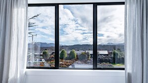 A room with a large window offering a view of a mountainous landscape and a garden.