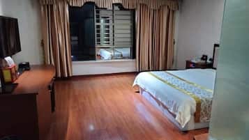 A hotel room with a bed, a desk, a television, and a window with curtains.