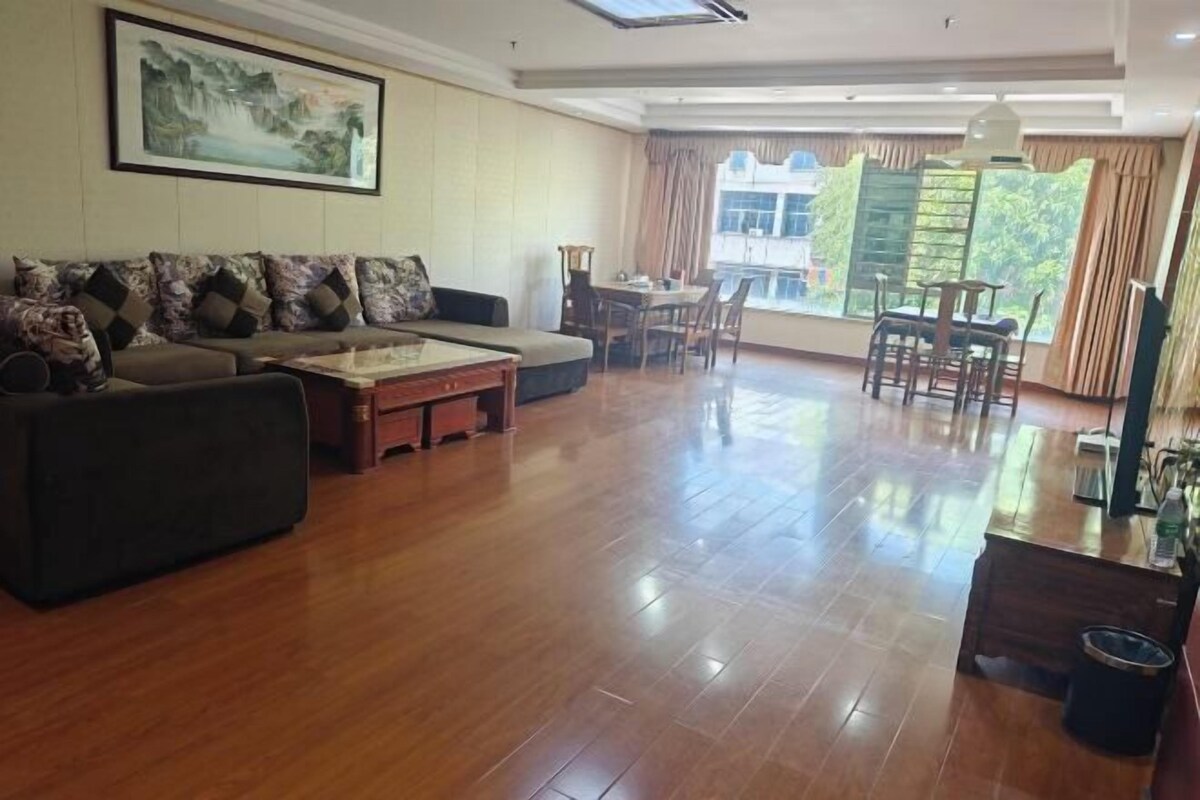 A spacious living room with a sofa set, a coffee table, and a dining area with chairs and a table.