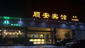 Entrada de hotel con un letrero de neón, una recepción y un área de estacionamiento.