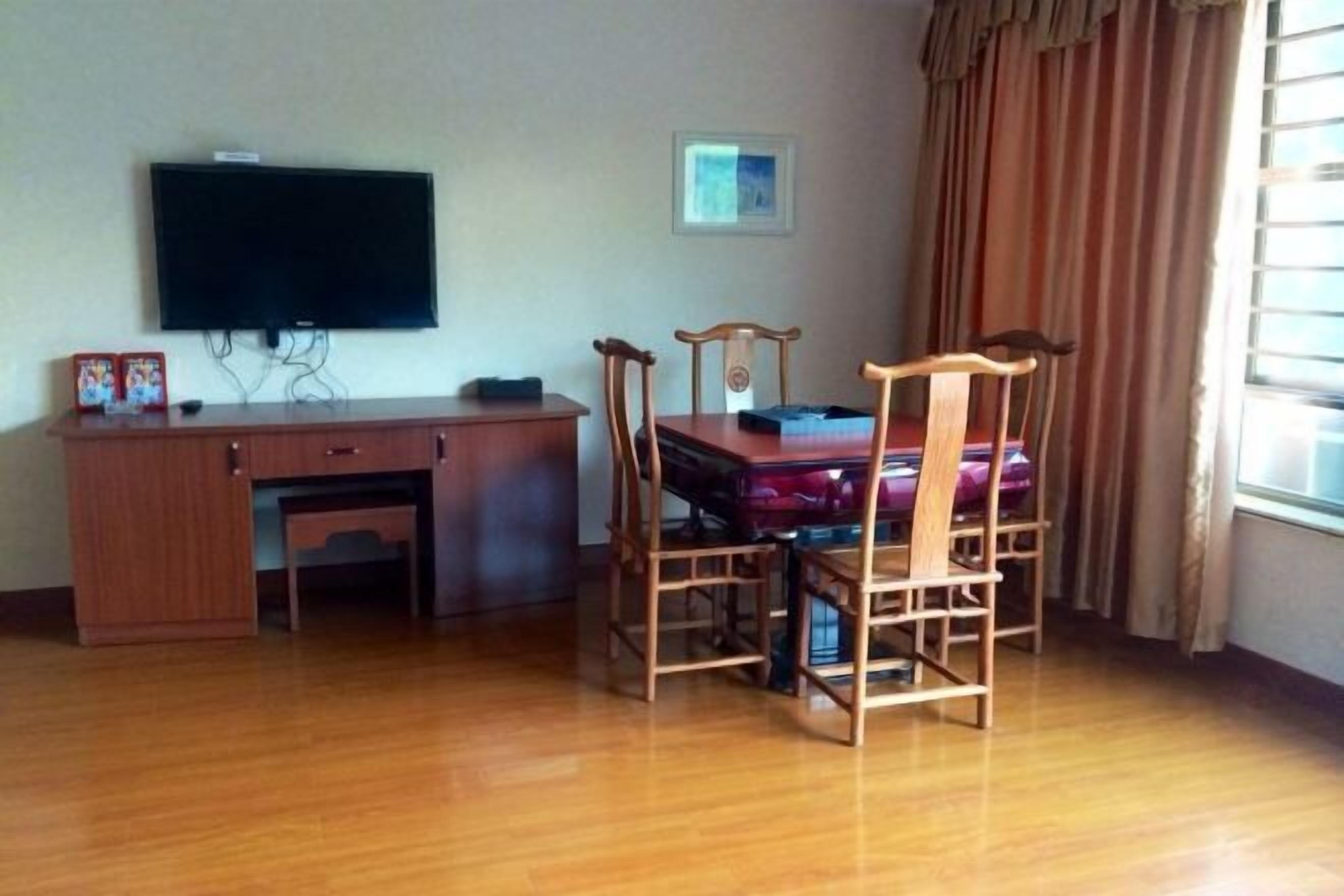 Ein Zimmer mit einem Holztisch, einem an der Wand montierten Fernseher und einem Esstisch mit Stühlen.