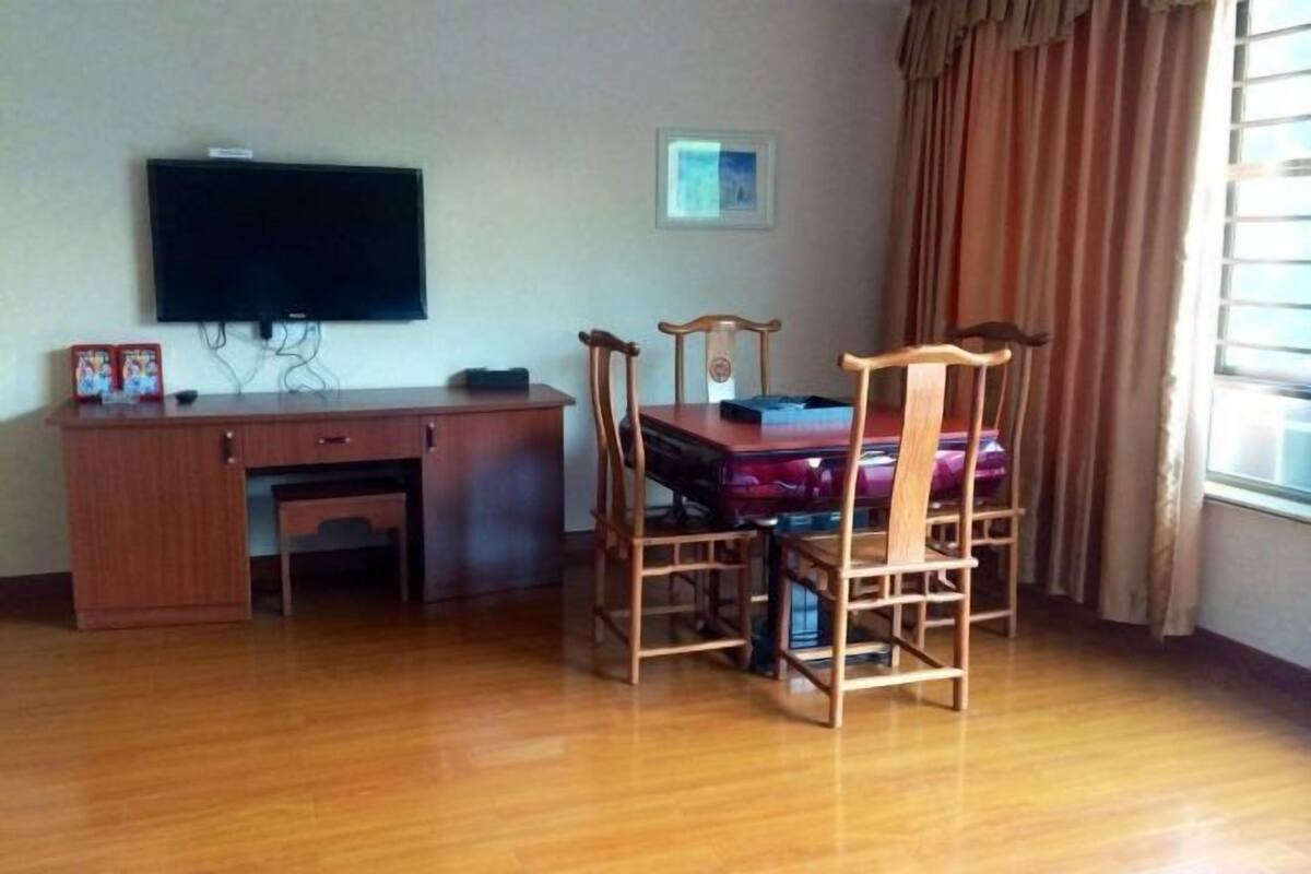 Ein Zimmer mit einem Holztisch, einem an der Wand montierten Fernseher und einem Esstisch mit Stühlen.